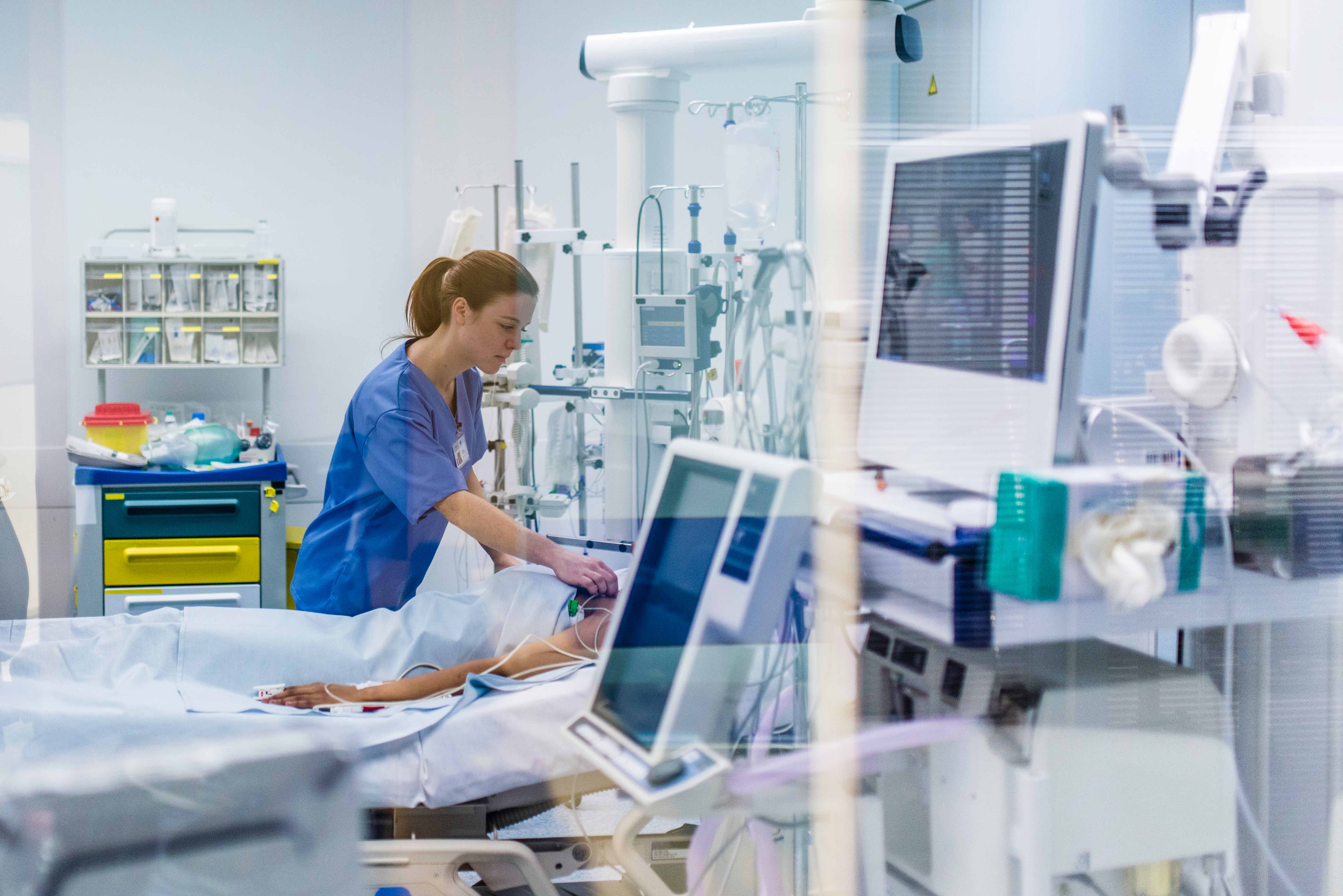 nurse monitoring patient that is in hospital bed