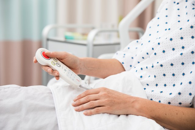 A patient in a hospital bed holding a pillow speaker