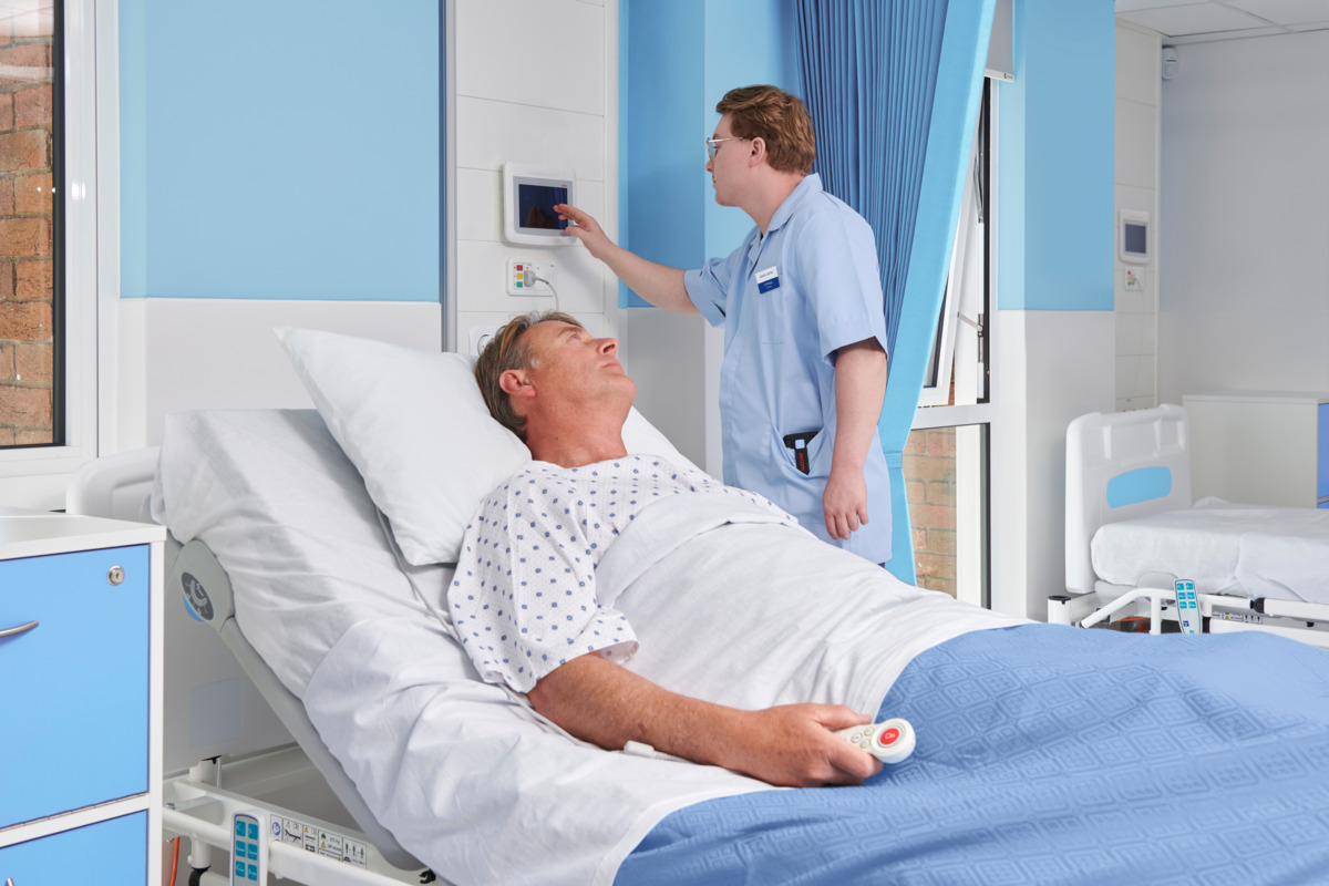 atient in hospital bed holding nurse call remote